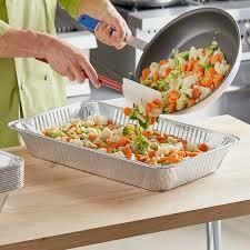 food being poured into a steam table pan for serving